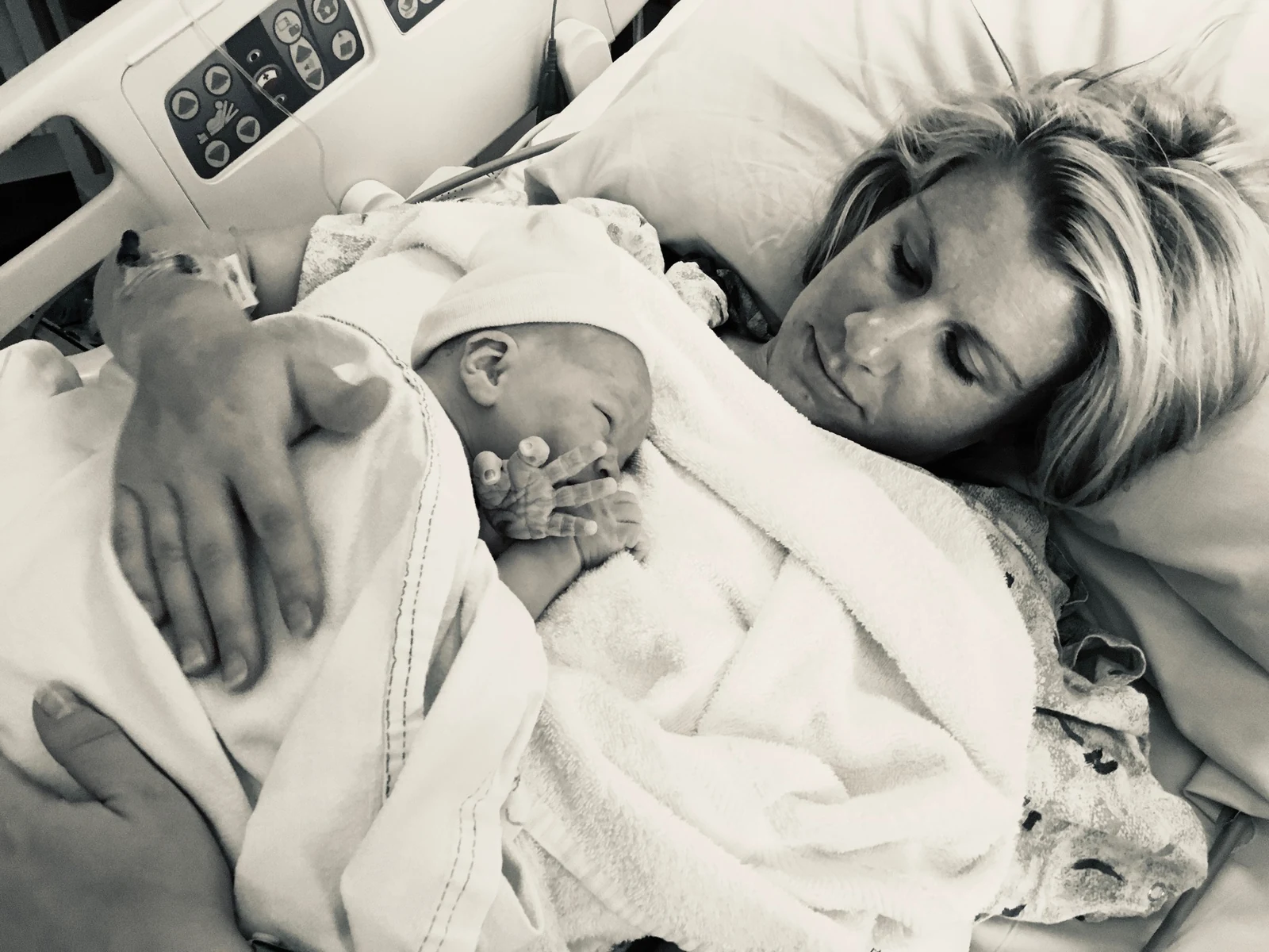 A parent resting with a newborn in a hospital bed