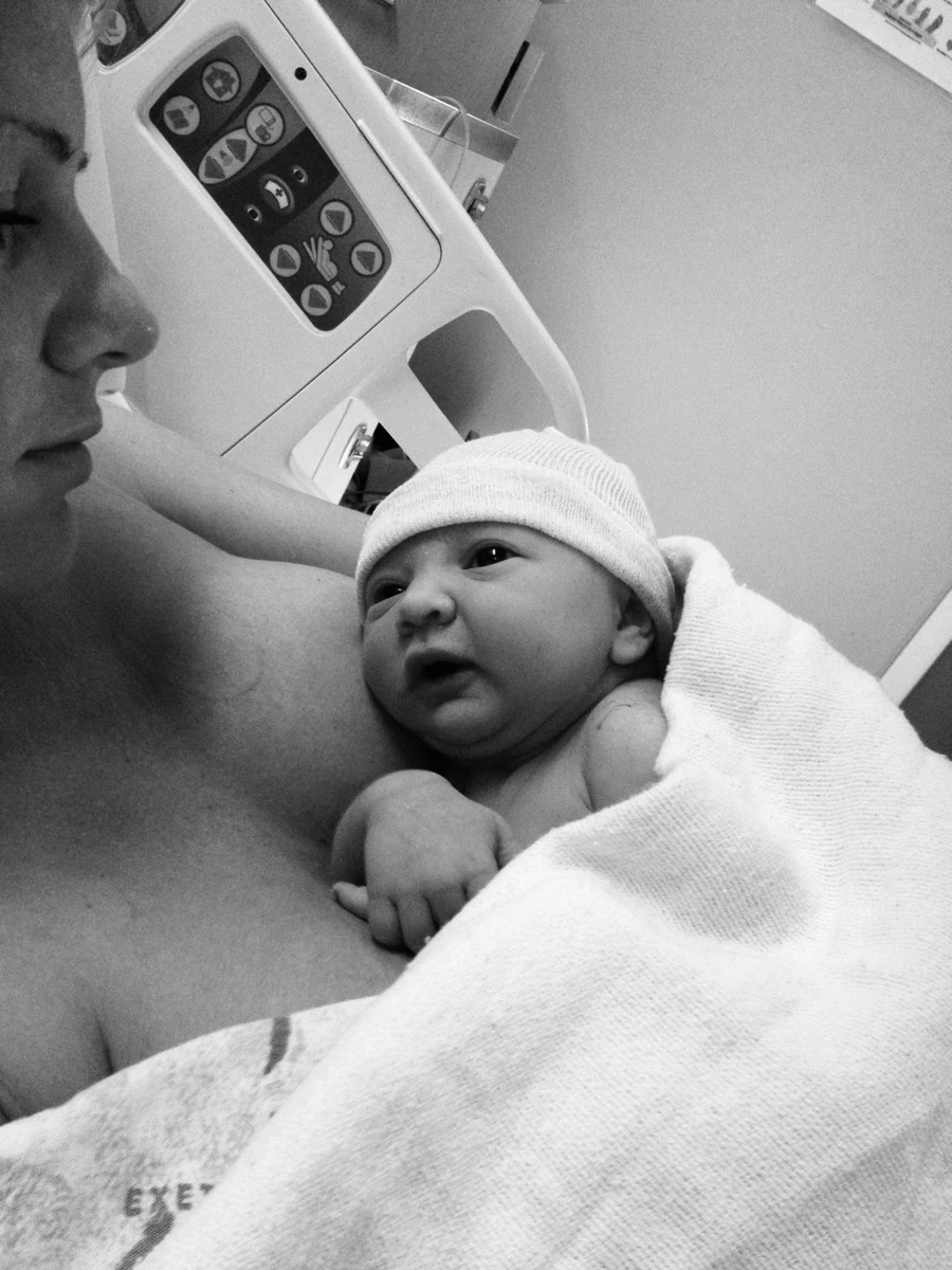 A newborn resting on a parent’s chest in a hospital room